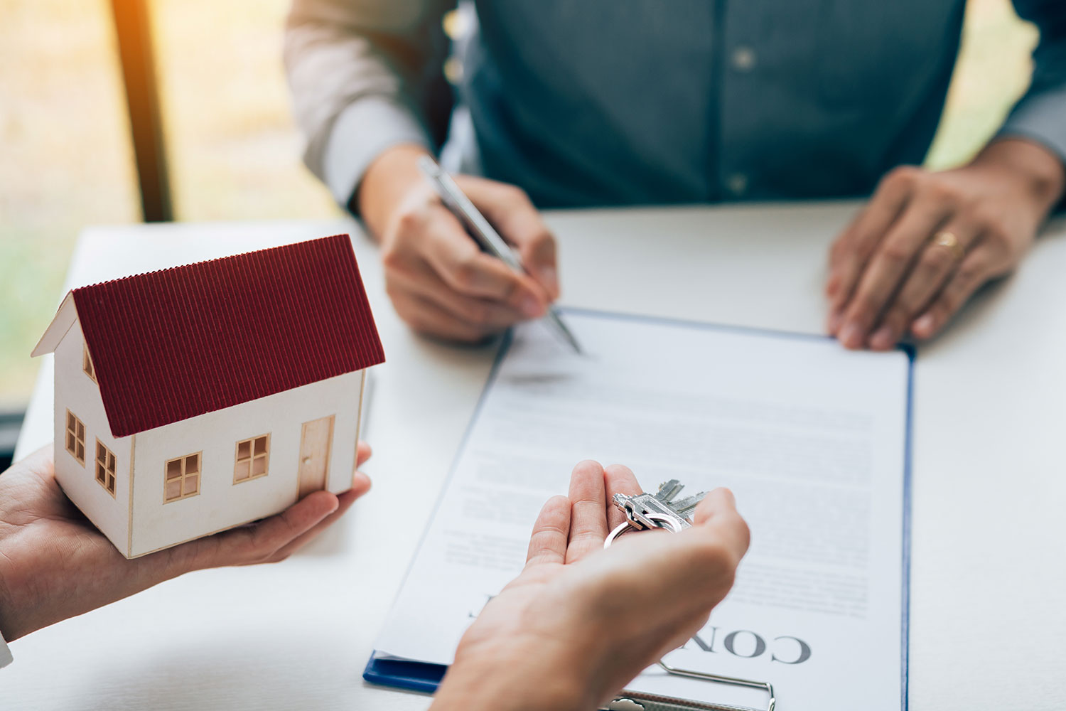 high-angle-view-man-signing-insurance-papers-by-model-home-paper-currency-table